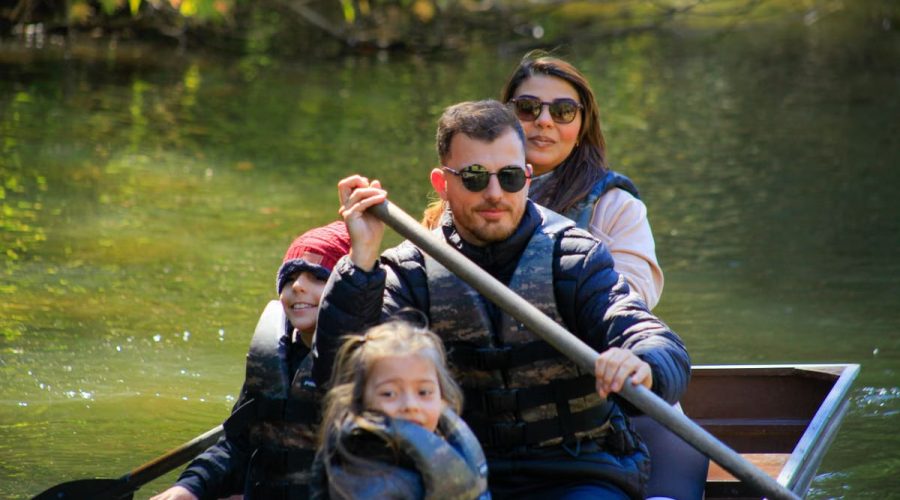 A family of four rowing a canoe on a serene lake during a sunny day, enjoying an outdoor adventure.